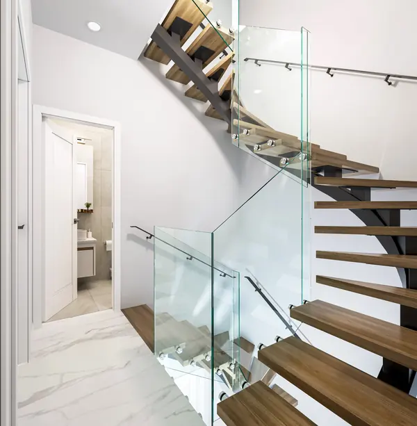The floating oak staircase with glass balustrade seen from the entrance hall, with the guest WC beyond